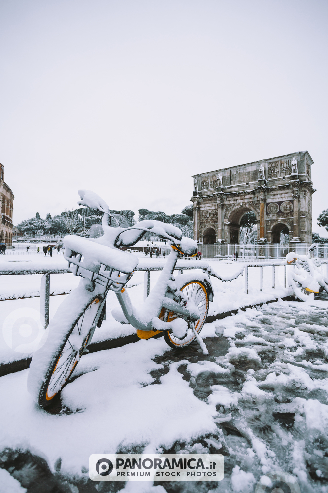 A lovely day of snow in Rome, Italy, 26th February 2018: a view of snowy bikes behind the Arch of Costantino